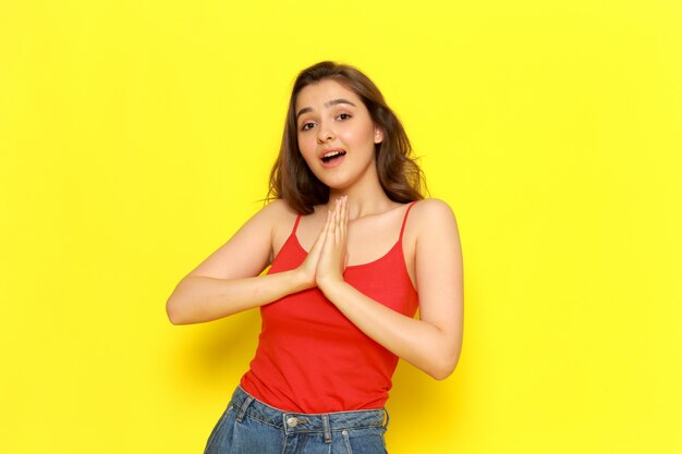 Una vista frontal joven bella dama en camisa roja y jeans azul posando con expresión emocionada