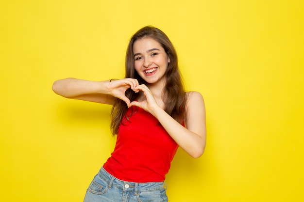 Foto gratuita una vista frontal joven bella dama en camisa roja y jeans azul posando y sonriendo