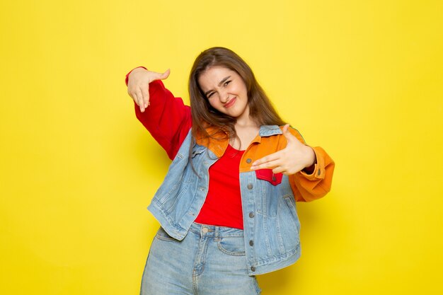 Una vista frontal joven y bella dama en camisa roja y jeans azul posando