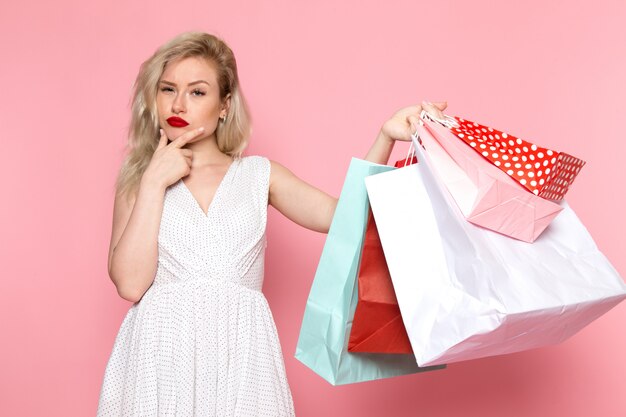 Una vista frontal joven bella dama en vestido blanco con paquetes de compras