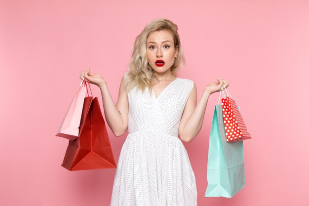 Una vista frontal joven bella dama en vestido blanco con paquetes de compras