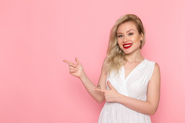 Una vista frontal joven bella dama en vestido blanco posando con una sonrisa en su rostro