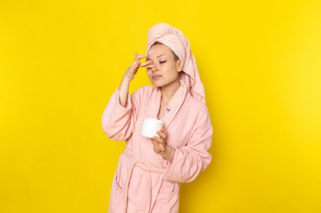 Una vista frontal joven y bella mujer en bata de baño rosa con crema