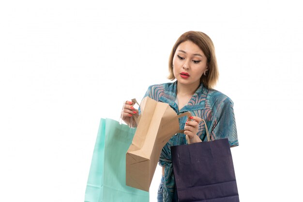 Una vista frontal joven y bella mujer en blusa de color azul jeans con paquetes de compras