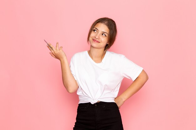 Una vista frontal joven y bella mujer en camisa blanca con la celebración de la tarjeta púrpura con una sonrisa