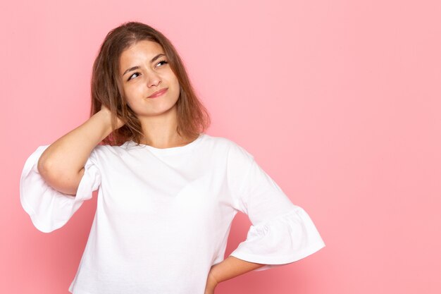 Una vista frontal joven y bella mujer en camisa blanca con expresión de pensamiento en su rostro posando