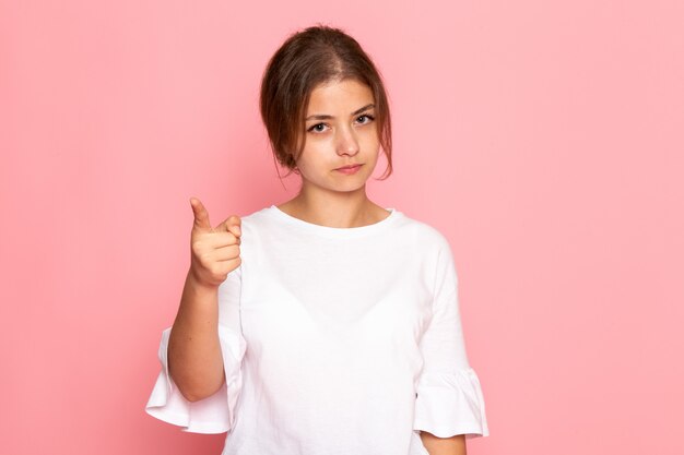 Una vista frontal joven y bella mujer en camisa blanca posando con expresión de advertencia