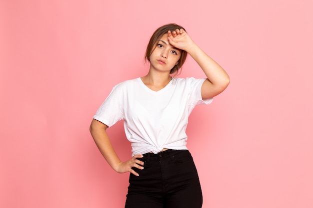 Una vista frontal joven y bella mujer en camisa blanca con posando con expresión cansada