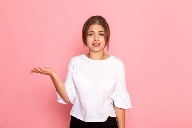 Una vista frontal joven y bella mujer en camisa blanca posando con expresión confusa