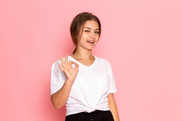 Una vista frontal joven y bella mujer en camisa blanca posando con expresión encantada