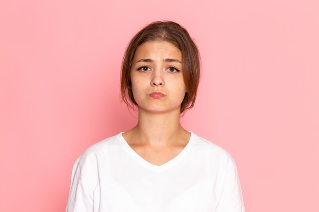 Una vista frontal joven y bella mujer en camisa blanca posando con expresión de tristeza