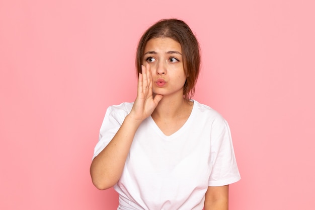 Una vista frontal joven y bella mujer en camisa blanca posando y susurrando