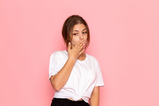 Una vista frontal joven y bella mujer en camisa blanca que cubre la boca