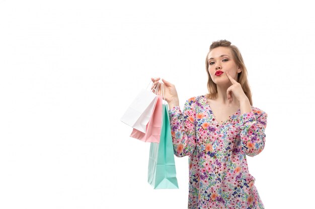 Una vista frontal joven y bella mujer en camisa de flores y pantalones negros con paquetes de compras posando