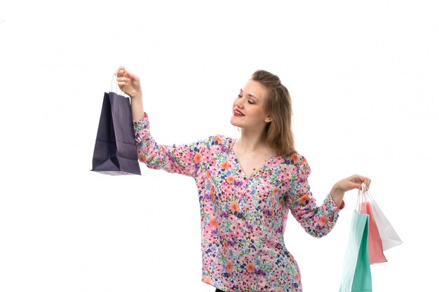 Una vista frontal joven y bella mujer en camisa de flores y pantalones negros con paquetes de compras posando