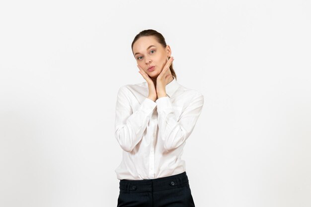 Vista frontal joven en blusa blanca con cara de coqueta sobre fondo blanco oficina de trabajo sentimiento femenino modelo emoción