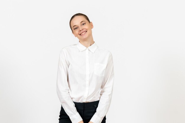 Vista frontal joven en blusa blanca sonriendo levemente sobre fondo blanco trabajo de oficina emoción femenina modelo de sentimiento