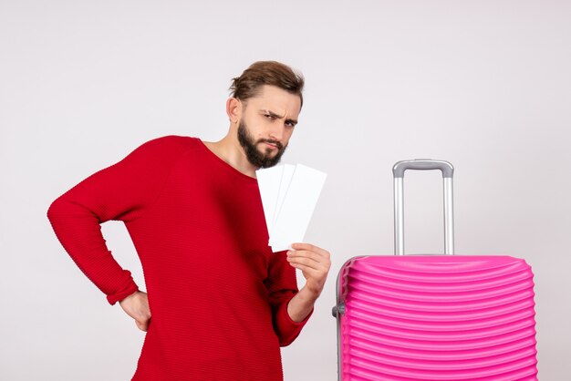 Vista frontal joven con bolsa rosa y sosteniendo boletos en la pared blanca viaje vuelo color viaje vacaciones turísticas