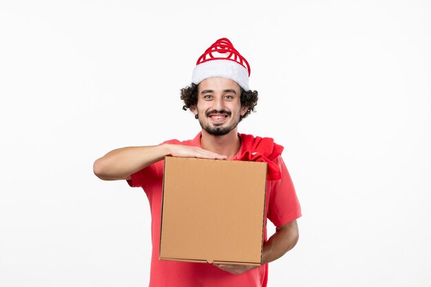 Vista frontal del joven con caja de comida de entrega en la pared blanca