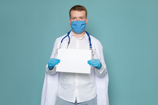 Foto gratuita una vista frontal joven en camisa blanca y guantes azules sosteniendo un trozo de papel en el espacio azul