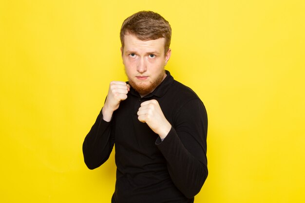 Vista frontal del joven en camisa negra posando con pose de boxeo