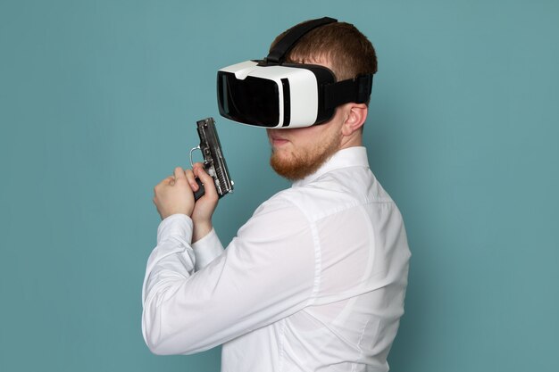 Una vista frontal joven en camiseta blanca con pistola jugando vr en el espacio azul