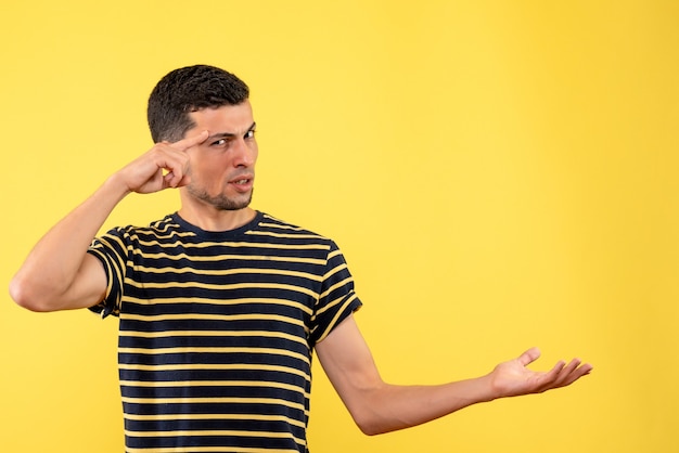 Vista frontal joven en camiseta a rayas blanco y negro fondo amarillo aislado con espacio de copia