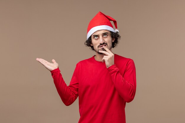 Vista frontal joven con cara de pensamiento sobre fondo marrón vacaciones emociones navidad