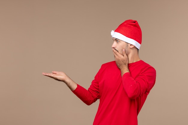 Vista frontal joven con cara de sorpresa sobre fondo marrón Navidad emoción vacaciones