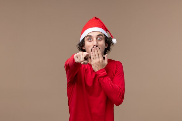 Vista frontal joven con cara de sorpresa sobre fondo marrón vacaciones emociones navidad