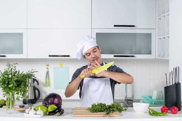 Vista frontal joven chef limpiando su cuchillo