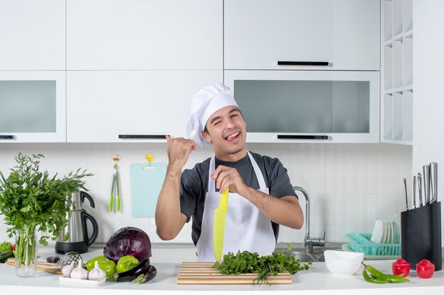 Vista frontal joven chef en uniforme apuntando al armario