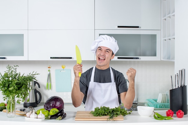 Vista frontal joven chef en uniforme disfrutando de la cocina