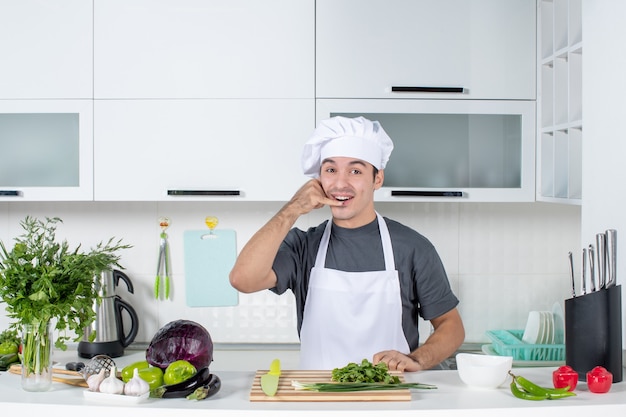 Vista frontal joven chef en uniforme haciendo gesto de llamarme teléfono