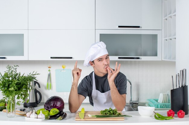 Vista frontal joven chef en uniforme haciendo signo de beso de chef