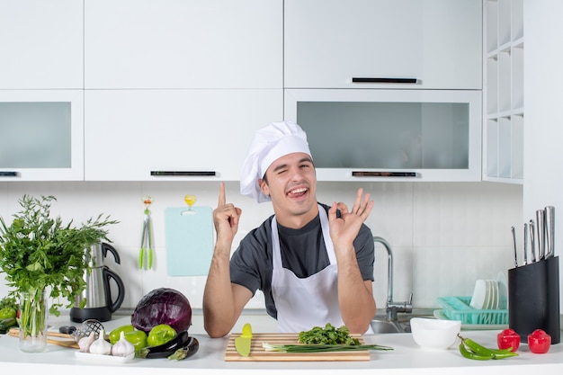 Vista frontal joven chef en uniforme haciendo signo okey