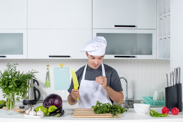 Vista frontal joven chef en uniforme mirando su mano