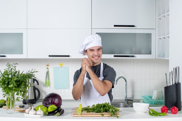 Vista frontal joven chef en uniforme uniendo las manos