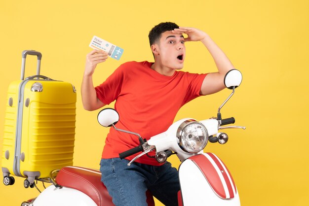 Vista frontal joven en ciclomotor sosteniendo billete observando