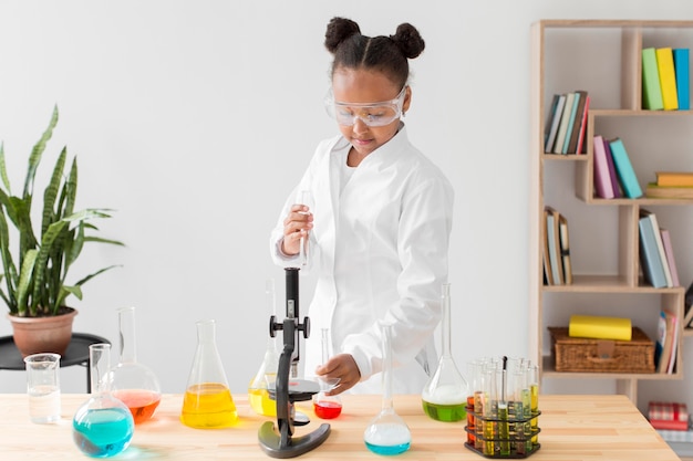 Vista frontal del joven científico en bata de laboratorio con pociones