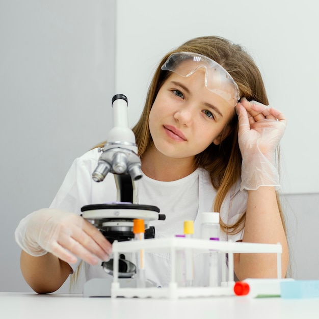 Vista frontal del joven científico posando mientras usa microscopio