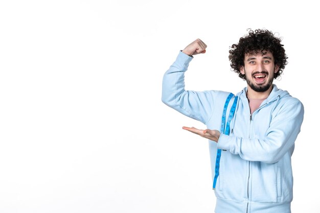 Vista frontal joven con cinta métrica flexionando sobre fondo blanco cuerpo muscular salud cintura adelgazamiento midiendo perder peso del torso humano