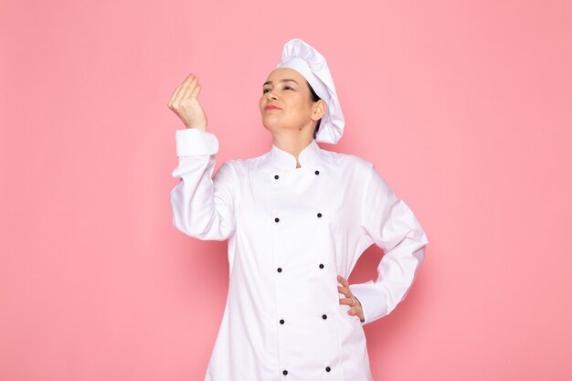 Una vista frontal joven cocinera en traje de cocinero blanco gorra blanca sonriendo posando feliz sabroso cartel