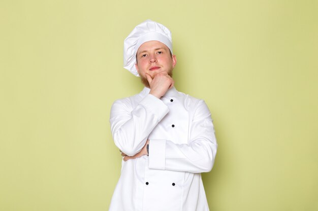 Una vista frontal joven cocinero masculino en traje de cocinero blanco gorra blanca posando pensando