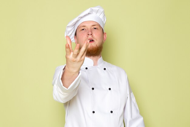 Una vista frontal joven cocinero masculino en traje de cocinero blanco gorra blanca