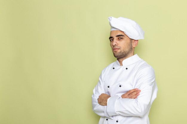 Vista frontal joven cocinero en traje de cocinero blanco posando