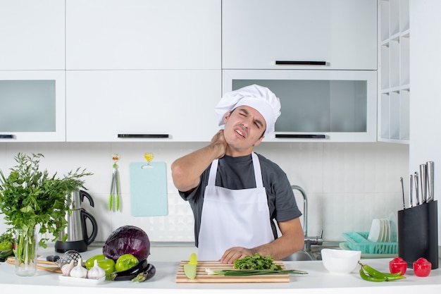 Vista frontal joven cocinero en uniforme sosteniendo su cuello