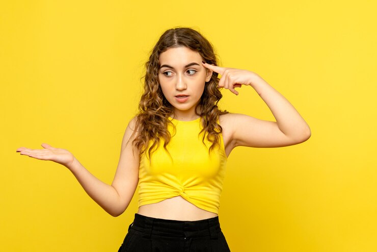 Foto gratuito vista frontal de la joven confundida en la pared amarilla