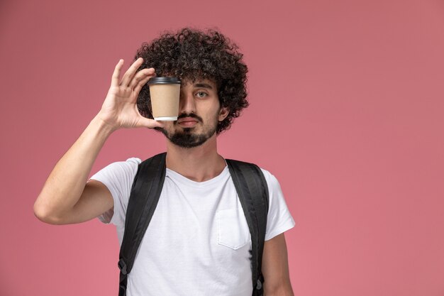 Vista frontal joven cubriendo su ojo con taza de café de papel