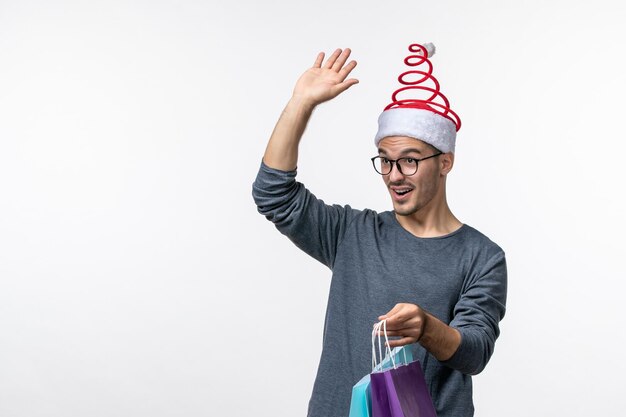 Vista frontal del joven después de las compras navideñas en la pared blanca